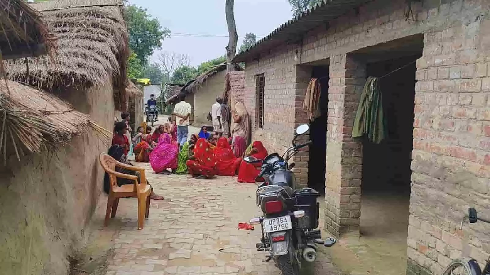 गांव की गली में घर के बाहर बैठे ग्रामीण और खड़ी मोटरसाइकिल की तस्वीर। गांव की गली में घर के बाहर बैठे ग्रामीण और खड़ी मोटरसाइकिल की तस्वीर।