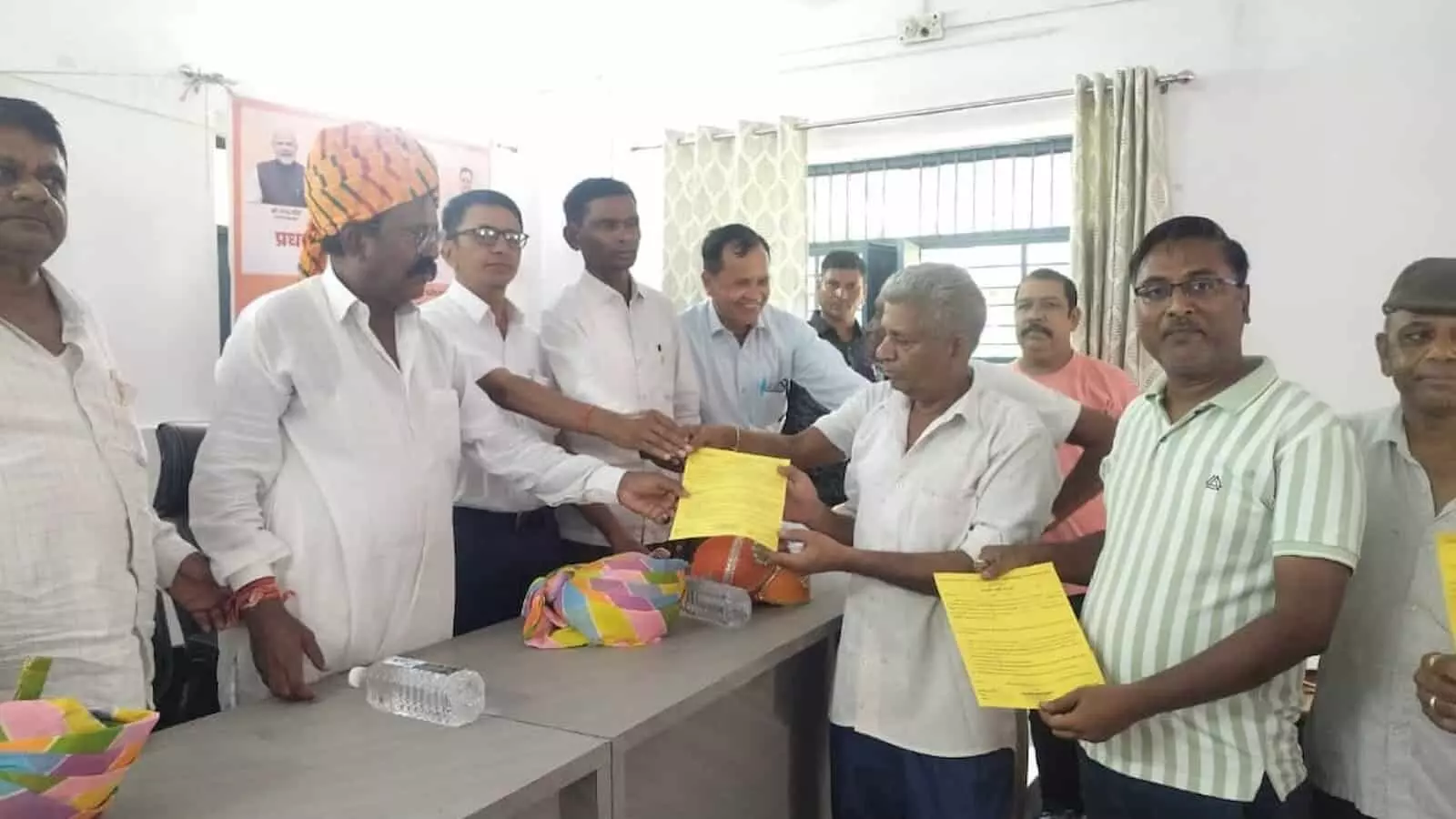 तस्वीर में एक कमरे के भीतर कुछ लोग अन्य व्यक्तियों को पीले प्रमाण-पत्र सौंप रहे हैं। तस्वीर में एक कमरे के भीतर कुछ लोग अन्य व्यक्तियों को पीले प्रमाण-पत्र सौंप रहे हैं।