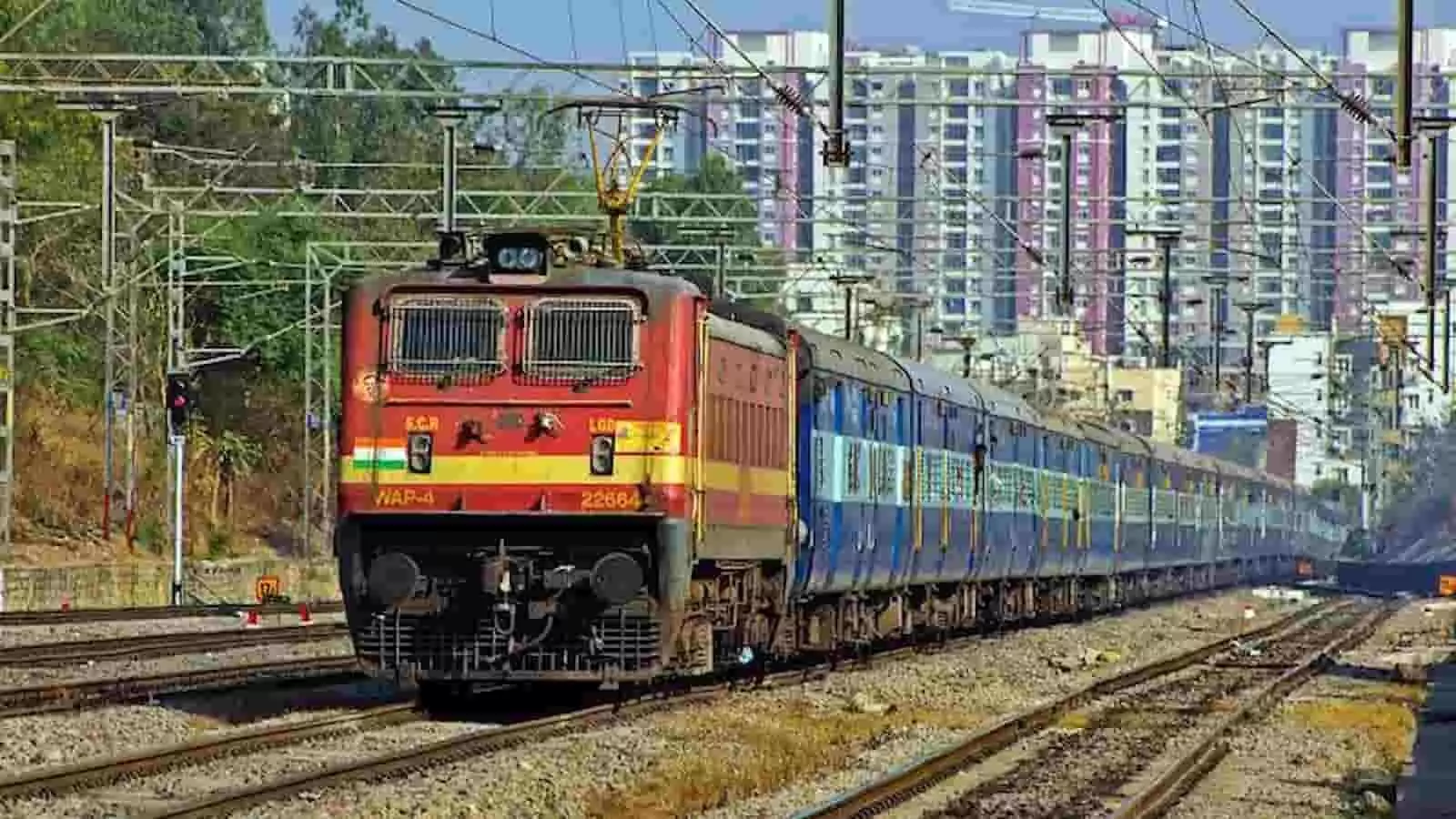 तस्वीर में रेलवे पटरी पर चलती हुई लाल इंजन वाली भारतीय ट्रेन दिख रही है। तस्वीर में रेलवे पटरी पर चलती हुई लाल इंजन वाली भारतीय ट्रेन दिख रही है।