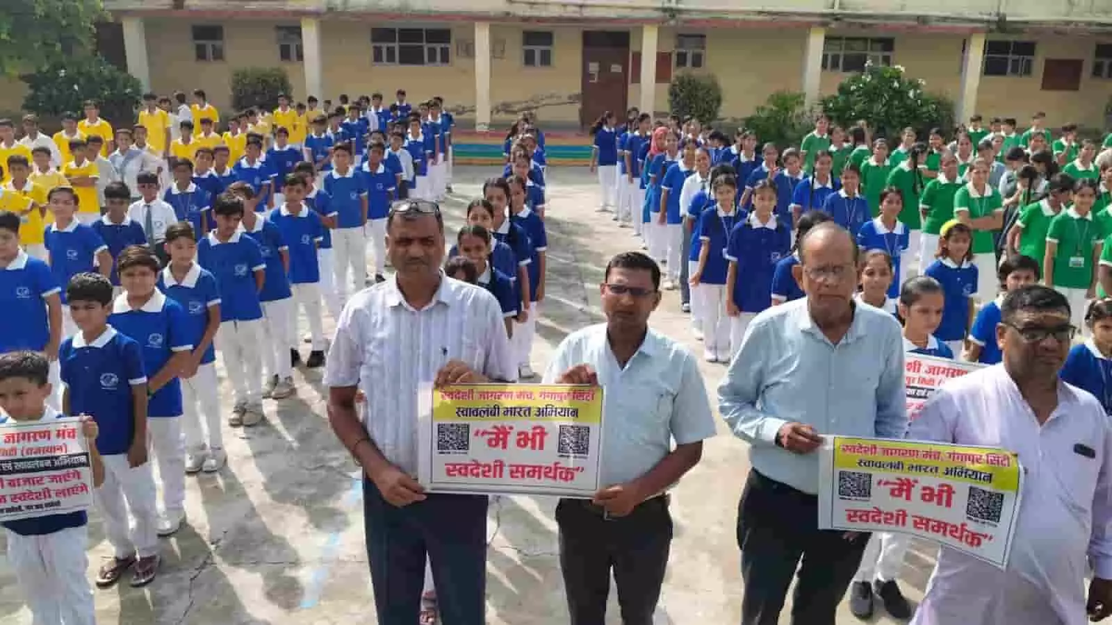 विद्यालय प्रांगण में स्वदेशी अभियान के पोस्टर हाथ में लिए खड़े लोग और पीछे कतारबद्ध छात्र। विद्यालय प्रांगण में स्वदेशी अभियान के पोस्टर हाथ में लिए खड़े लोग और पीछे कतारबद्ध छात्र।