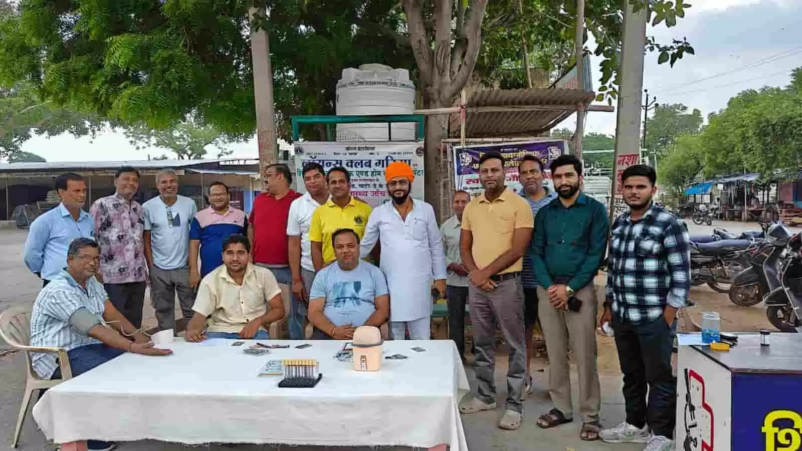 तस्वीर में गंगापुर सिटी में स्वास्थ्य जांच शिविर के दौरान मेज के पास खड़े लोग। तस्वीर में गंगापुर सिटी में स्वास्थ्य जांच शिविर के दौरान मेज के पास खड़े लोग।