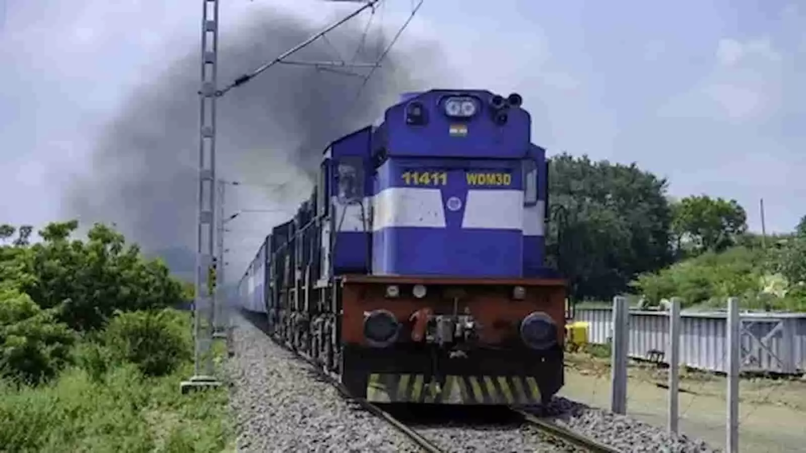 तस्वीर में पटरियों पर दौड़ती हुई एक नीले रंग की भारतीय रेलवे की ट्रेन दिखाई दे रही है। तस्वीर में पटरियों पर दौड़ती हुई एक नीले रंग की भारतीय रेलवे की ट्रेन दिखाई दे रही है।