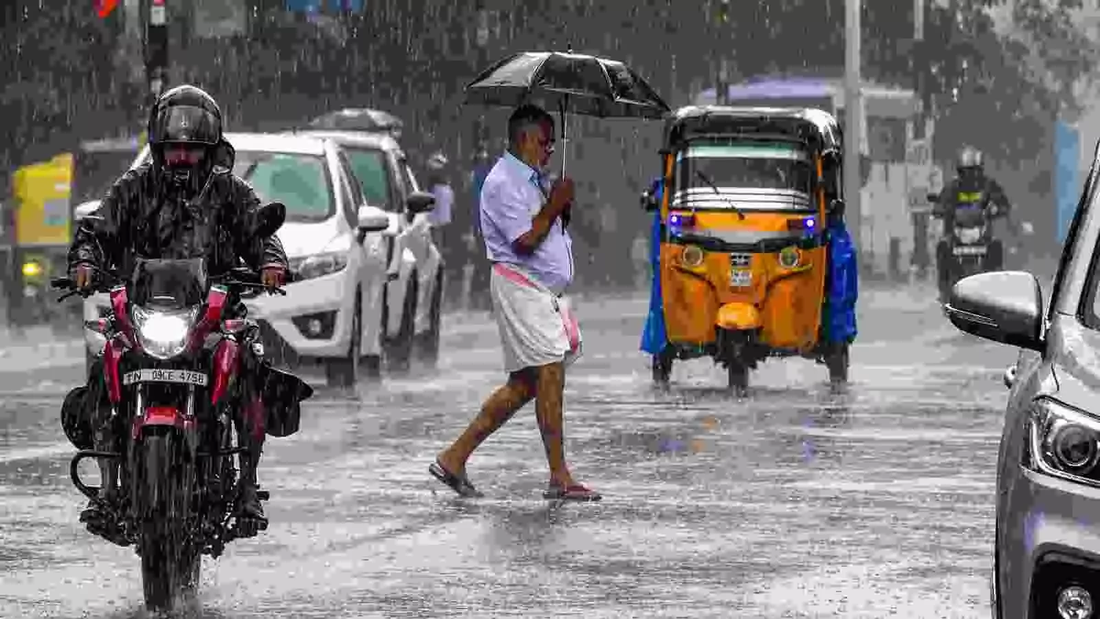 बारिश के बीच सड़क पर चलते वाहन और राहगीर दक्षिण भारत में खराब मौसम के संदर्भ में। बारिश के बीच सड़क पर चलते वाहन और राहगीर दक्षिण भारत में खराब मौसम के संदर्भ में।