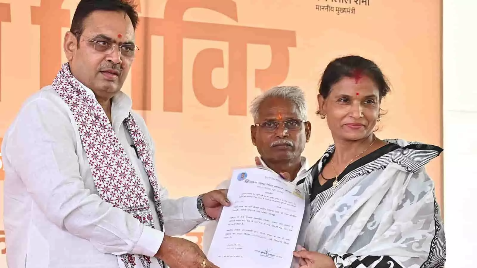 तस्वीर में मुख्यमंत्री भजनलाल शर्मा एक महिला को दस्तावेज सौंपते हुए नजर आ रहे हैं। तस्वीर में मुख्यमंत्री भजनलाल शर्मा एक महिला को दस्तावेज सौंपते हुए नजर आ रहे हैं।