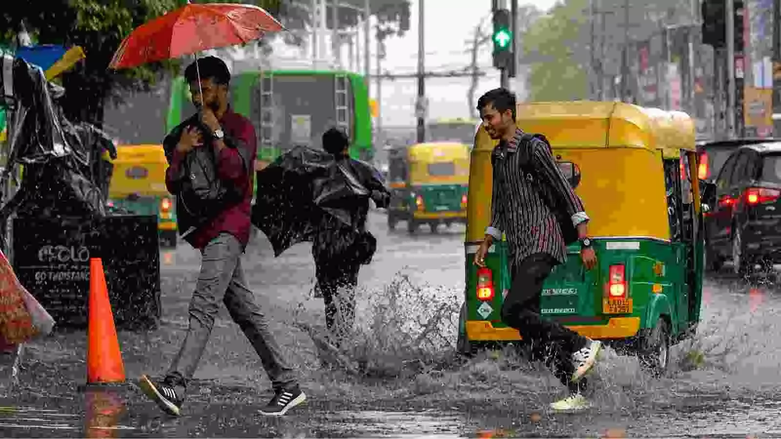 सड़कों पर पानी के बीच से गुजरते लोग, दक्षिण भारत में सक्रिय मानसून के दौरान। सड़कों पर पानी के बीच से गुजरते लोग, दक्षिण भारत में सक्रिय मानसून के दौरान।