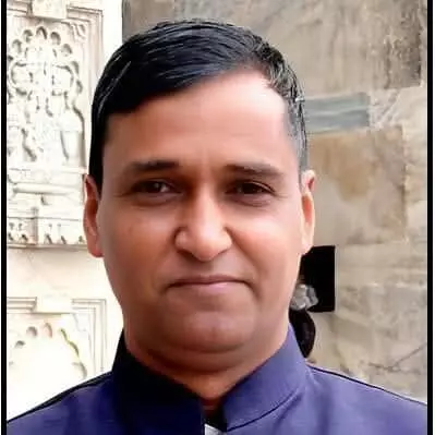 तस्वीर में मंदिर के परिसर में खड़े एक व्यक्ति को नीले वस्त्रों में देखा जा सकता है। तस्वीर में मंदिर के परिसर में खड़े एक व्यक्ति को नीले वस्त्रों में देखा जा सकता है।