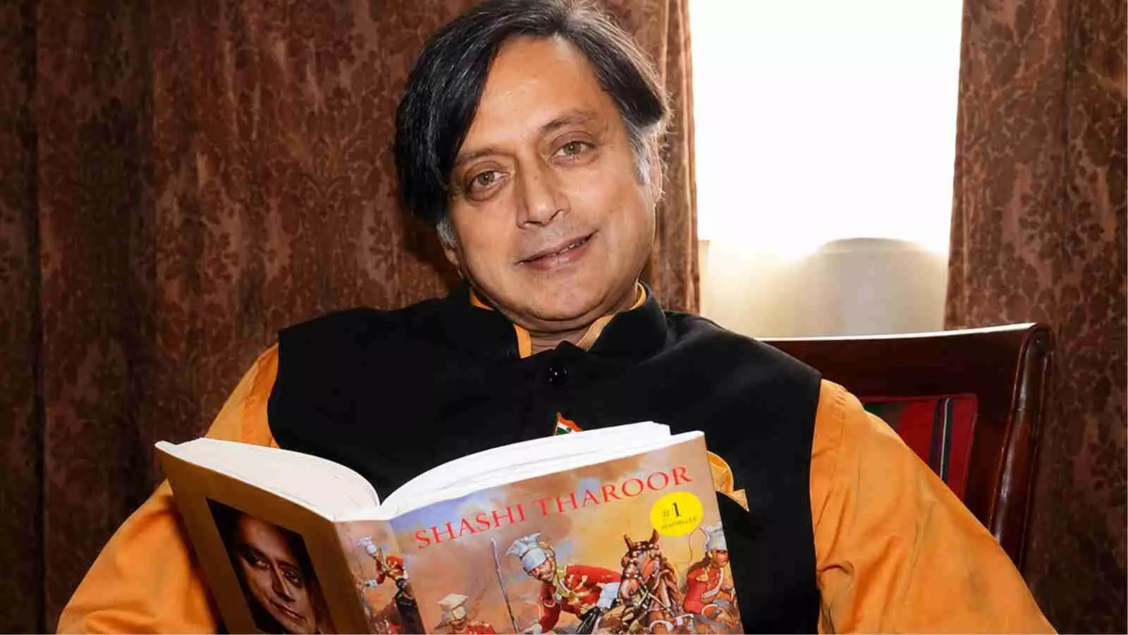 कांग्रेस नेता शशि थरूर किताब पकड़े हुए बैठे हैं भाषा विवाद पर दिए गए बयान के संदर्भ में। कांग्रेस नेता शशि थरूर किताब पकड़े हुए बैठे हैं भाषा विवाद पर दिए गए बयान के संदर्भ में।
