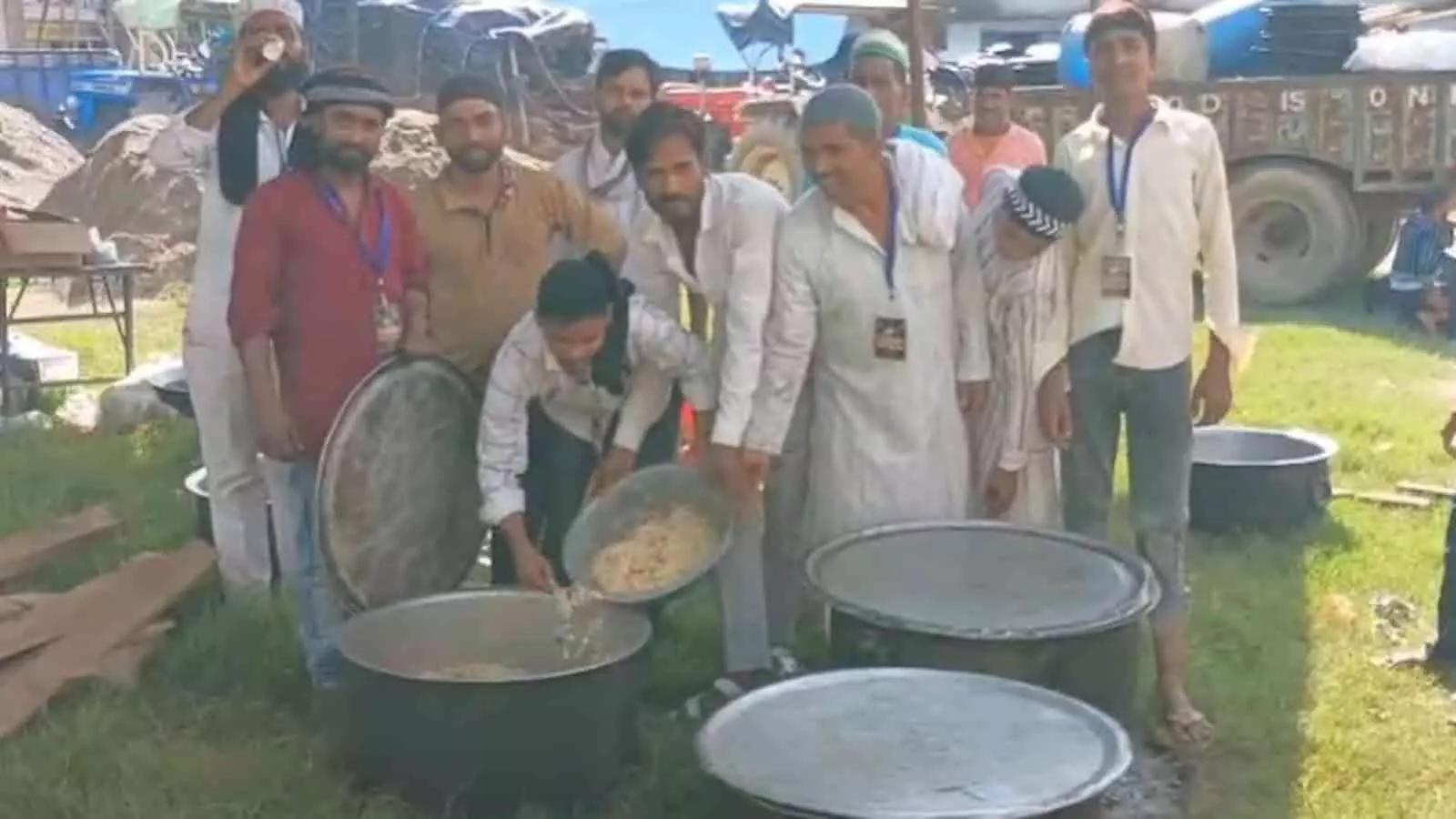 तस्वीर में खुले मैदान में बड़े बर्तनों के पास खड़े लोग नजर आ रहे हैं। तस्वीर में खुले मैदान में बड़े बर्तनों के पास खड़े लोग नजर आ रहे हैं।