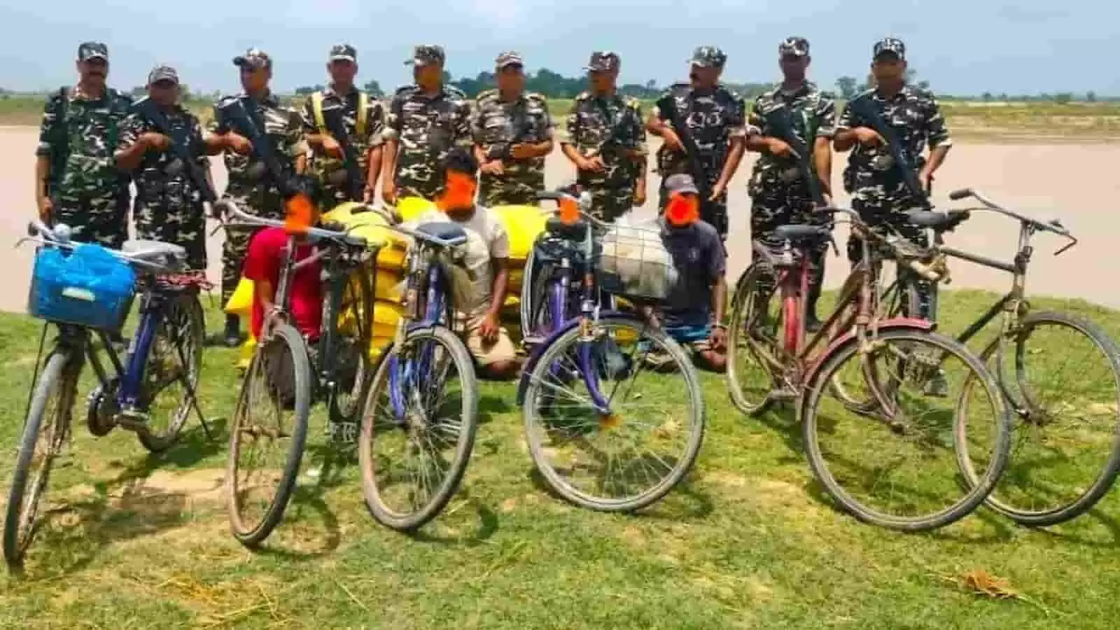 तस्वीर में सशस्त्र सीमा बल के जवान, पकड़े गए तस्कर, साइकिलें और यूरिया की बोरियां नदी किनारे दिख रही हैं। तस्वीर में सशस्त्र सीमा बल के जवान, पकड़े गए तस्कर, साइकिलें और यूरिया की बोरियां नदी किनारे दिख रही हैं।