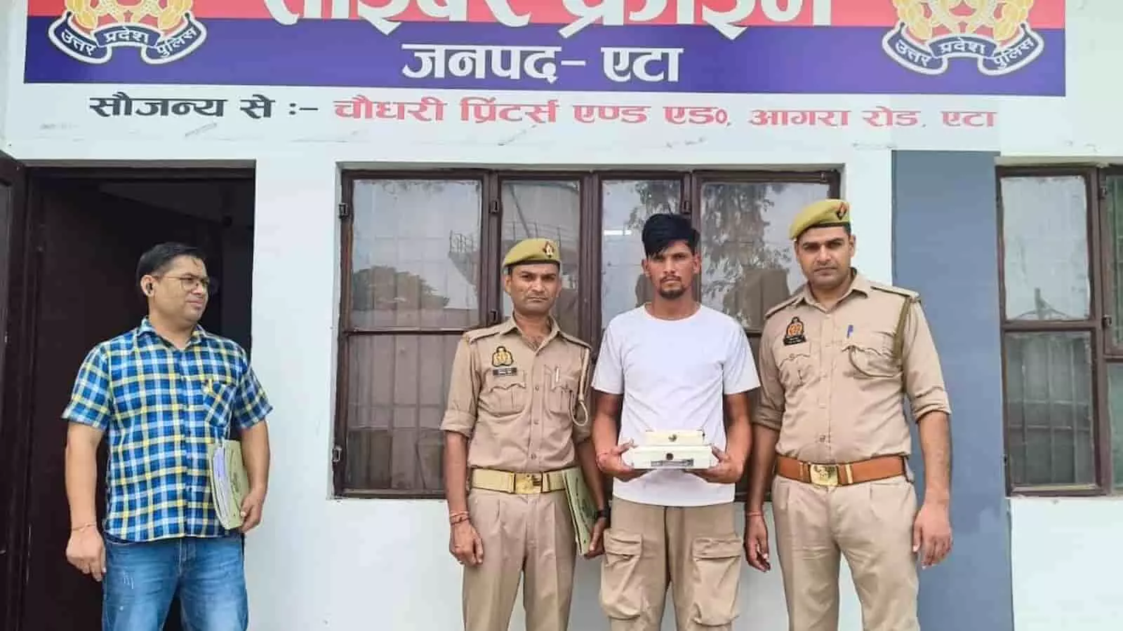तस्वीर में एटा के थाना साइबर क्राइम के बाहर पुलिसकर्मियों के साथ खड़ा गिरफ्तार आरोपी। तस्वीर में एटा के थाना साइबर क्राइम के बाहर पुलिसकर्मियों के साथ खड़ा गिरफ्तार आरोपी।