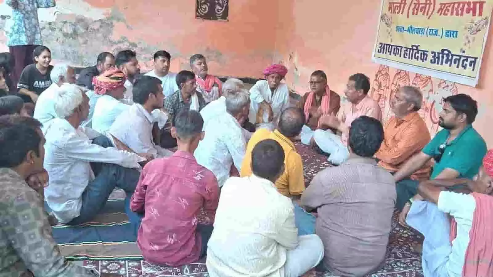 तस्वीर में माली महासभा की बैठक के दौरान जमीन पर बैठकर चर्चा करते लोग दिख रहे हैं। तस्वीर में माली महासभा की बैठक के दौरान जमीन पर बैठकर चर्चा करते लोग दिख रहे हैं।