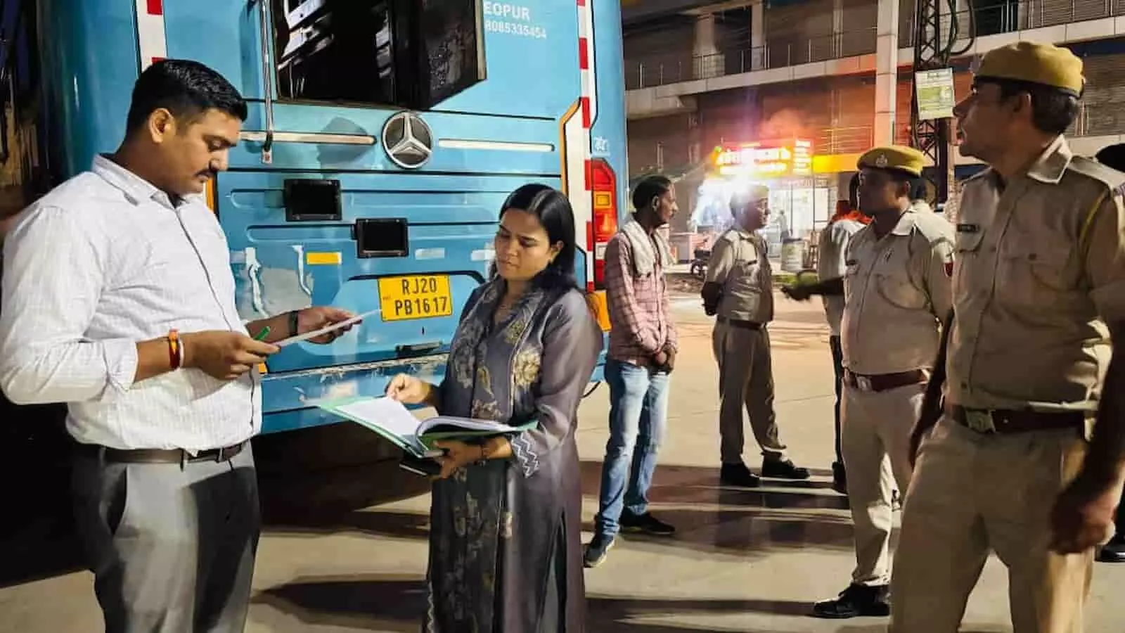 तस्वीर में अधिकारी एक बस के पास दस्तावेजों की जांच करते हुए और पुलिसकर्मी नजर आ रहे हैं। तस्वीर में अधिकारी एक बस के पास दस्तावेजों की जांच करते हुए और पुलिसकर्मी नजर आ रहे हैं।