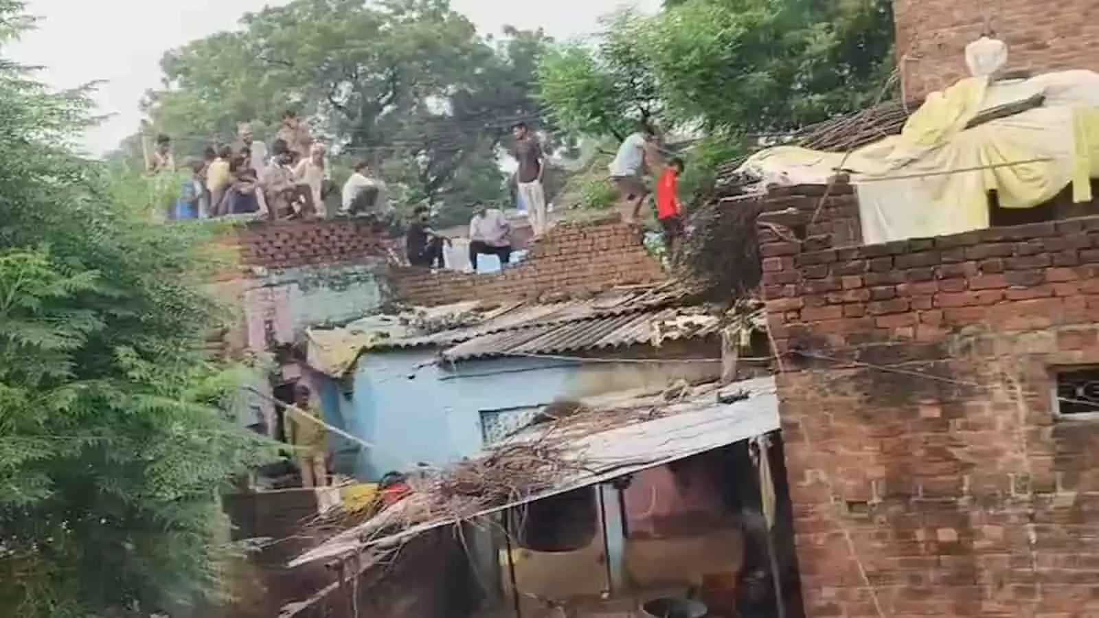 तस्वीर में लोग छतों पर खड़े दिखाई दे रहे हैं, आसपास ईंट के मकान हैं। तस्वीर में लोग छतों पर खड़े दिखाई दे रहे हैं, आसपास ईंट के मकान हैं।