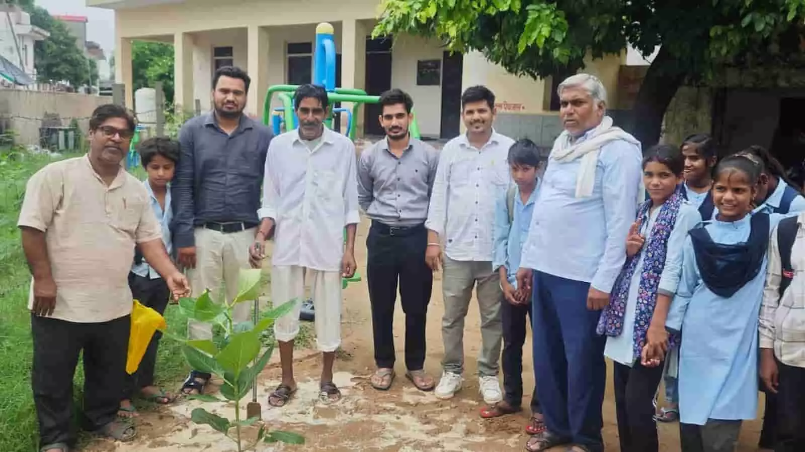 तस्वीर में छात्र और वयस्क विद्यालय परिसर में पौधे के पास खड़े हैं। तस्वीर में छात्र और वयस्क विद्यालय परिसर में पौधे के पास खड़े हैं।