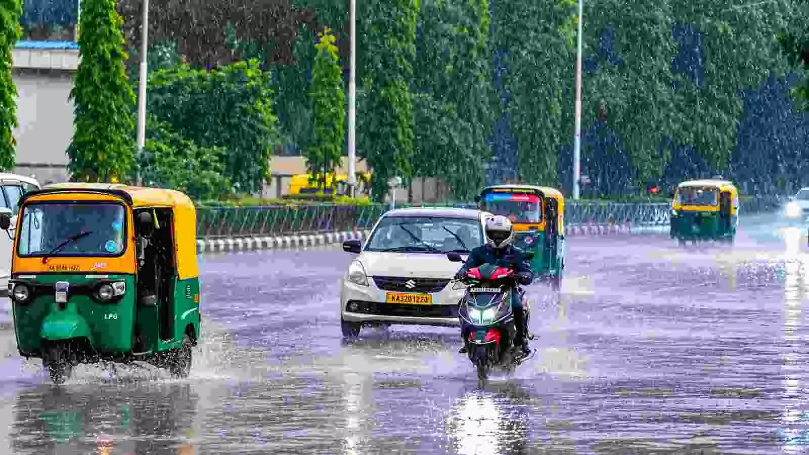 बारिश के दौरान कर्नाटक की सड़क पर वाहन चलाते लोग| बारिश के दौरान कर्नाटक की सड़क पर वाहन चलाते लोग|