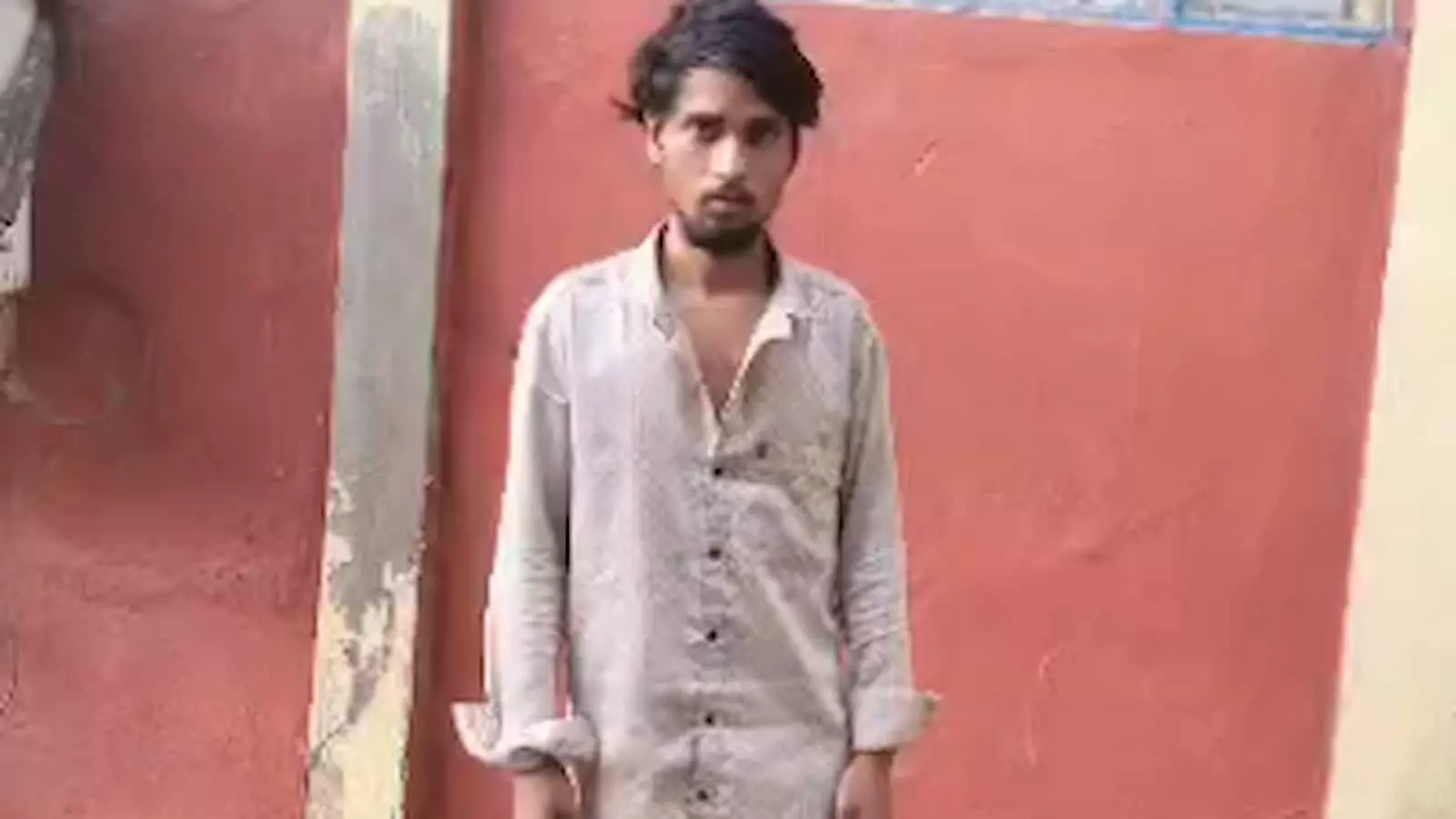 तस्वीर में एक युवक लाल दीवार के सामने खड़ा दिखाई दे रहा है। तस्वीर में एक युवक लाल दीवार के सामने खड़ा दिखाई दे रहा है।