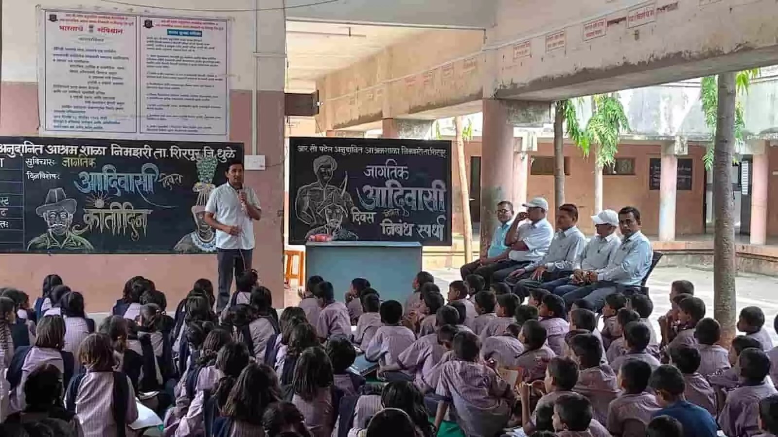 तस्वीर में आश्रम शाला के कार्यक्रम में भाषण देते वक्ता और बैठे हुए विद्यार्थी दिख रहे हैं। तस्वीर में आश्रम शाला के कार्यक्रम में भाषण देते वक्ता और बैठे हुए विद्यार्थी दिख रहे हैं।