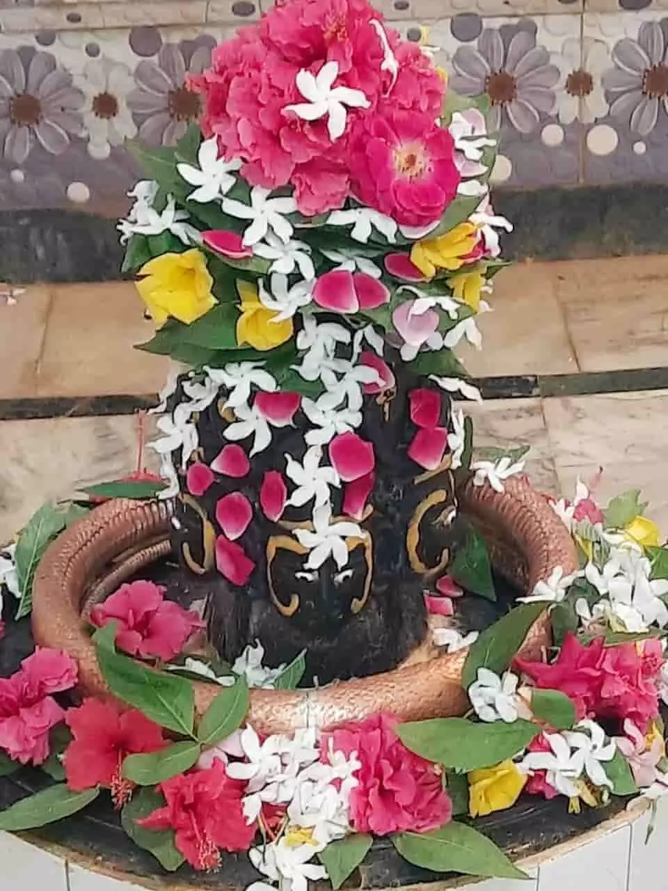 तस्वीर में फूलों और पत्तों से सजा हुआ पंचमुखी महादेव का शिवलिंग दिख रहा है। तस्वीर में फूलों और पत्तों से सजा हुआ पंचमुखी महादेव का शिवलिंग दिख रहा है।