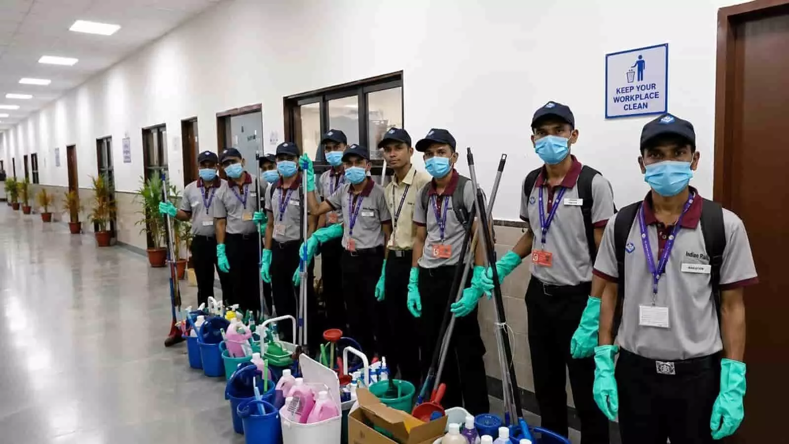 यूनिफॉर्म और मास्क पहने सफाई कर्मचारी सफाई उपकरणों के साथ स्टेशन के कॉरिडोर में खड़े हैं। यूनिफॉर्म और मास्क पहने सफाई कर्मचारी सफाई उपकरणों के साथ स्टेशन के कॉरिडोर में खड़े हैं।