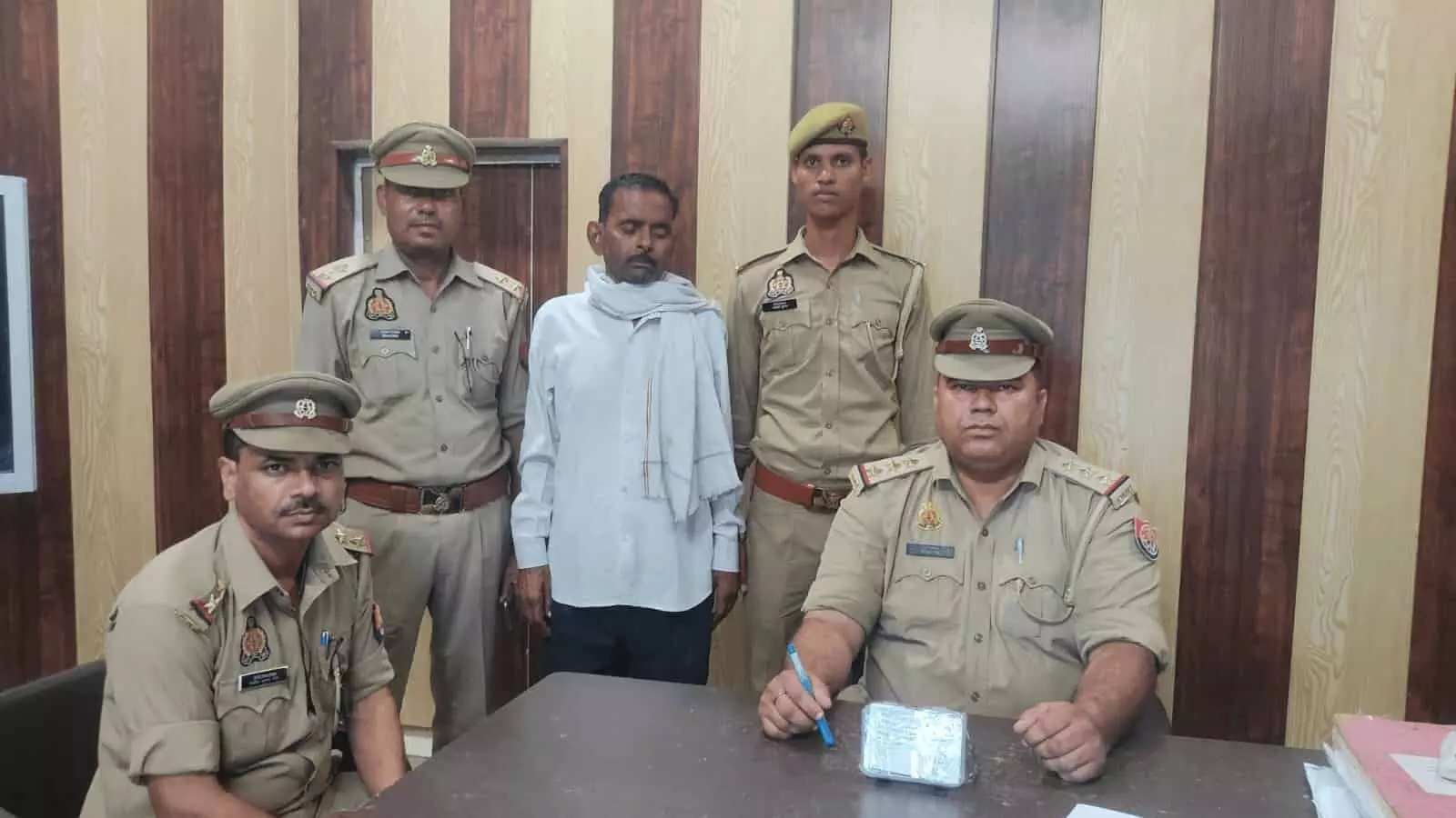 पुलिस कार्यालय में पुलिसकर्मियों के साथ एक व्यक्ति और मेज पर बरामद वस्तु दिख रही है। पुलिस कार्यालय में पुलिसकर्मियों के साथ एक व्यक्ति और मेज पर बरामद वस्तु दिख रही है।