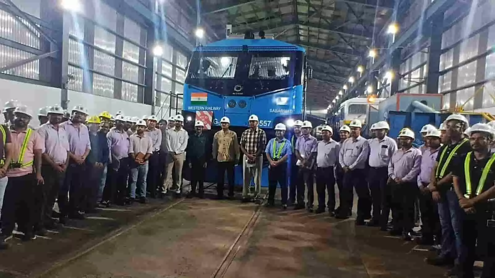 नीले लोकोमोटिव के सामने शेड में खड़े रेलवे अधिकारियों का एक बड़ा समूह। नीले लोकोमोटिव के सामने शेड में खड़े रेलवे अधिकारियों का एक बड़ा समूह।
