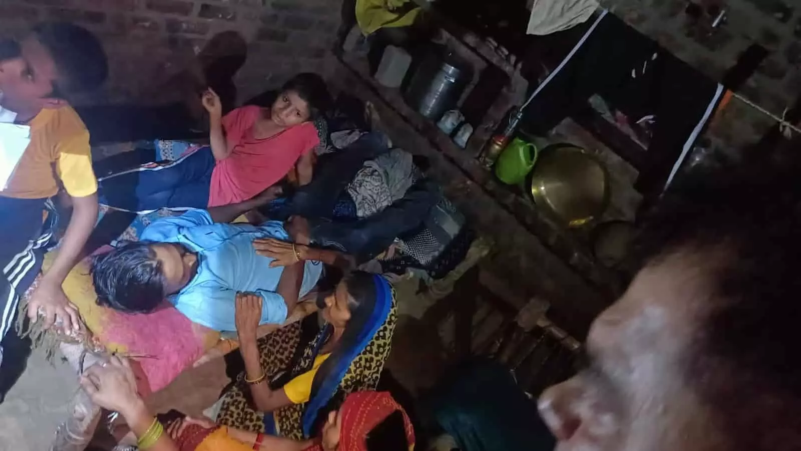 कमरे में लोग जमीन पर लेटे व्यक्ति के पास बैठे दिखाई दे रहे हैं। कमरे में लोग जमीन पर लेटे व्यक्ति के पास बैठे दिखाई दे रहे हैं।