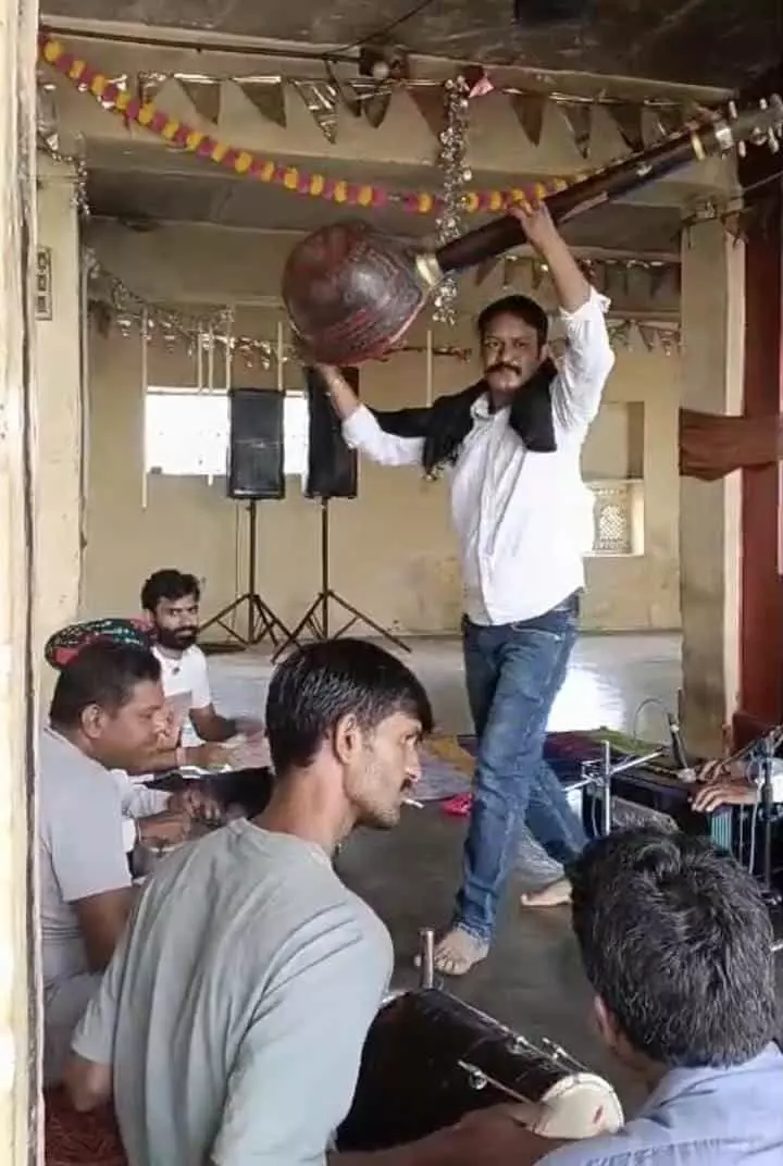 तस्वीर में जोगेश्वर बावजी स्थान नवा खेड़ा में सत्संग के दौरान तानपुरा उठाए एक व्यक्ति और बैठे हुए श्रद्धालु दिख रहे हैं। तस्वीर में जोगेश्वर बावजी स्थान नवा खेड़ा में सत्संग के दौरान तानपुरा उठाए एक व्यक्ति और बैठे हुए श्रद्धालु दिख रहे हैं।