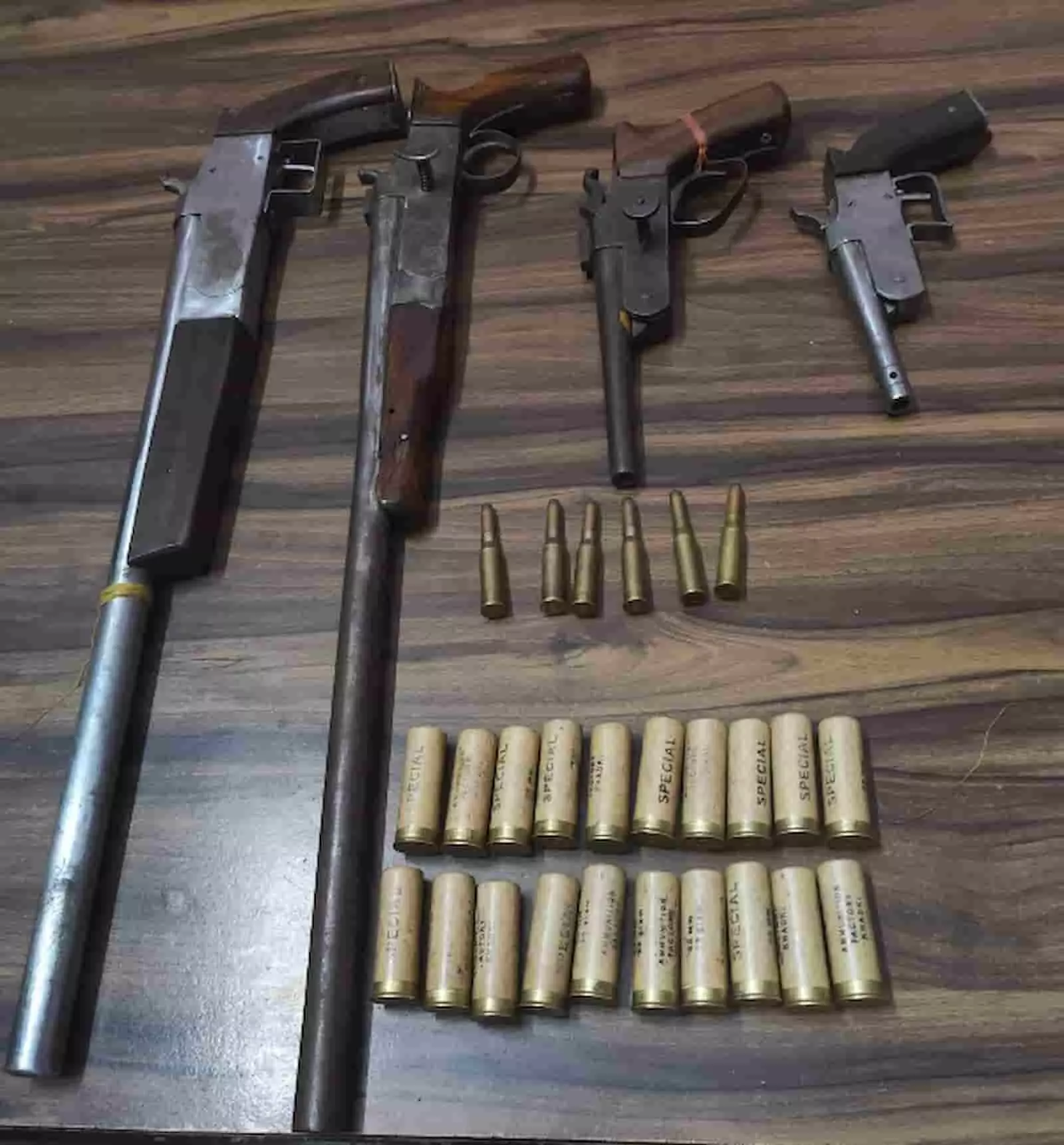 तस्वीर में लकड़ी की सतह पर रखे गए चार अवैध हथियार और जिंदा कारतूस दिख रहे हैं। तस्वीर में लकड़ी की सतह पर रखे गए चार अवैध हथियार और जिंदा कारतूस दिख रहे हैं।