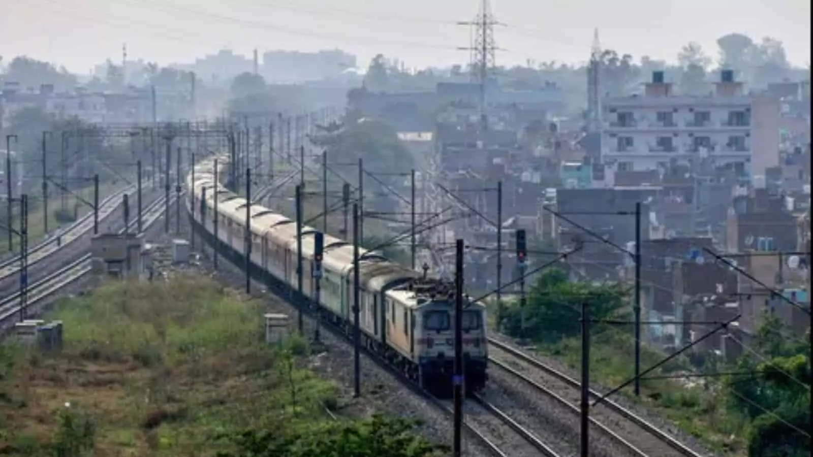 तस्वीर में रेलवे ट्रैक पर एक ट्रेन शहरी क्षेत्र से गुजरती हुई दिखाई दे रही है। तस्वीर में रेलवे ट्रैक पर एक ट्रेन शहरी क्षेत्र से गुजरती हुई दिखाई दे रही है।