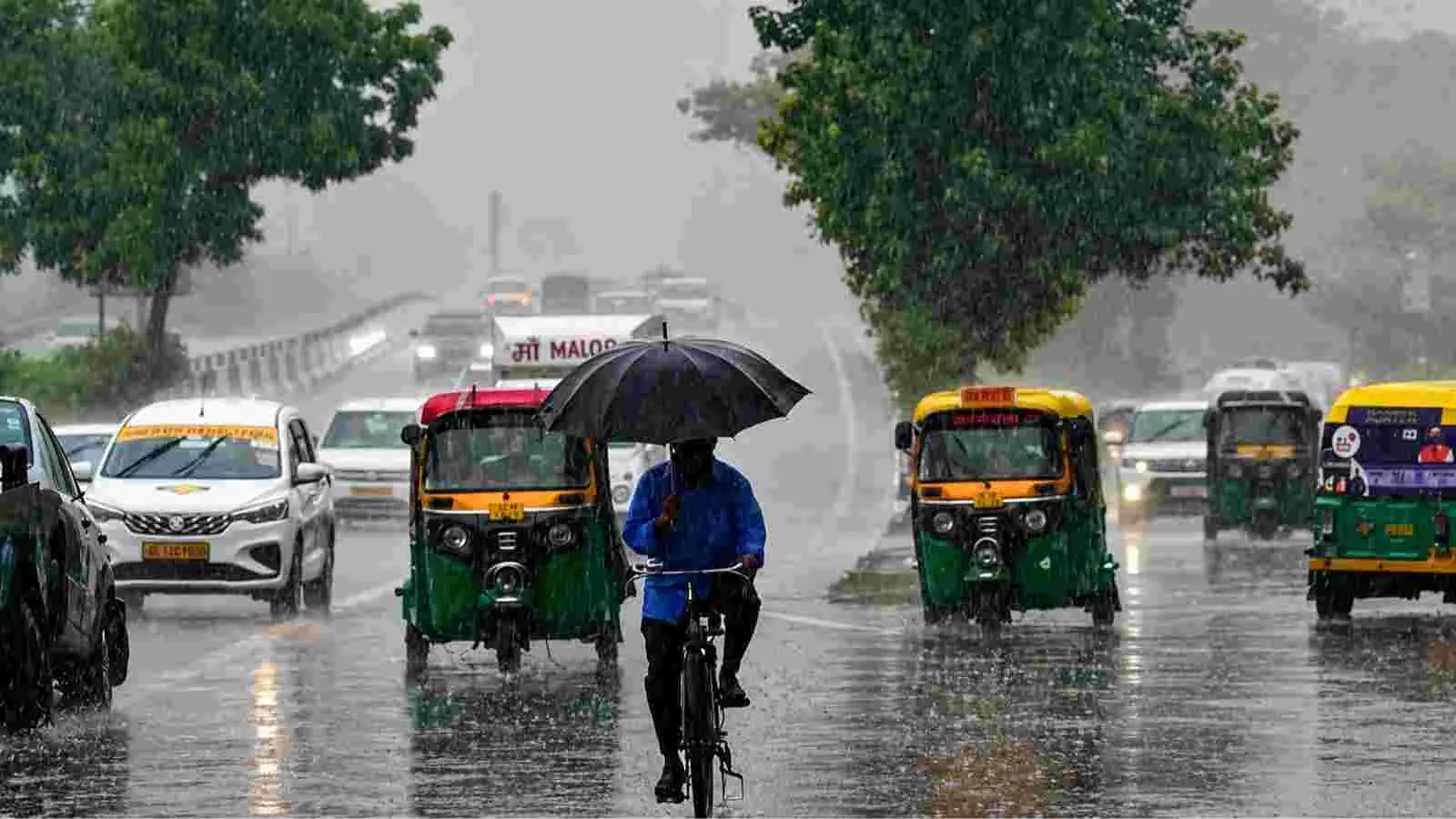 बारिश के दौरान सड़क पर चलते वाहन और साइकिल चालक दिल्ली में मौसम में बदलाव के संदर्भ में। बारिश के दौरान सड़क पर चलते वाहन और साइकिल चालक दिल्ली में मौसम में बदलाव के संदर्भ में।