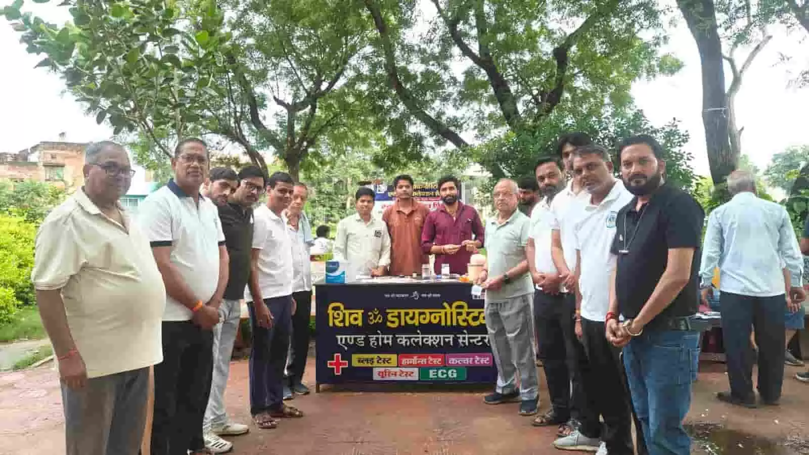 तस्वीर में गंगापुर सिटी में स्वास्थ्य जांच शिविर के दौरान बैनर के सामने खड़े लोग। तस्वीर में गंगापुर सिटी में स्वास्थ्य जांच शिविर के दौरान बैनर के सामने खड़े लोग।