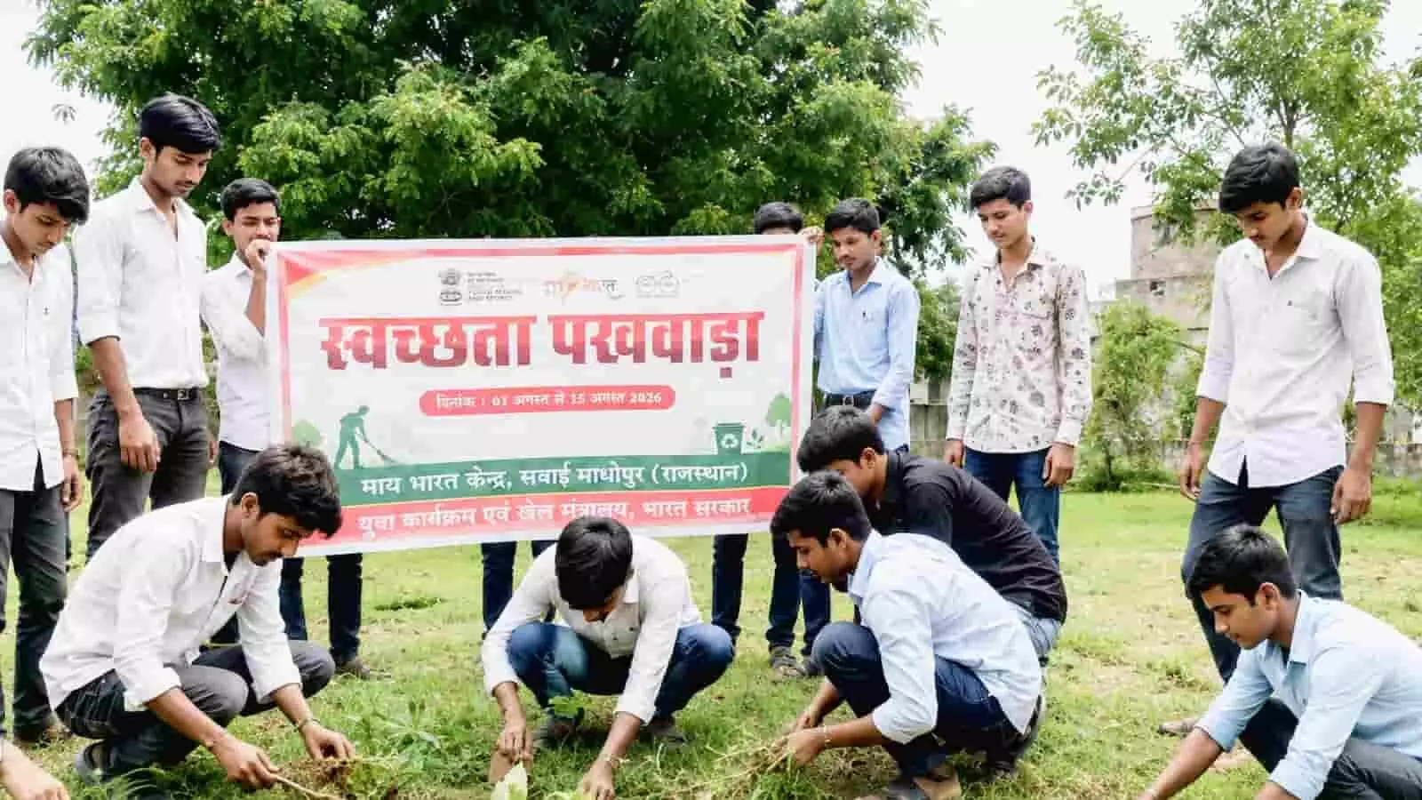स्वयंसेवक स्वच्छता पखवाड़ा का बैनर पकड़े हुए और मैदान में श्रमदान कर रहे हैं। स्वयंसेवक स्वच्छता पखवाड़ा का बैनर पकड़े हुए और मैदान में श्रमदान कर रहे हैं।