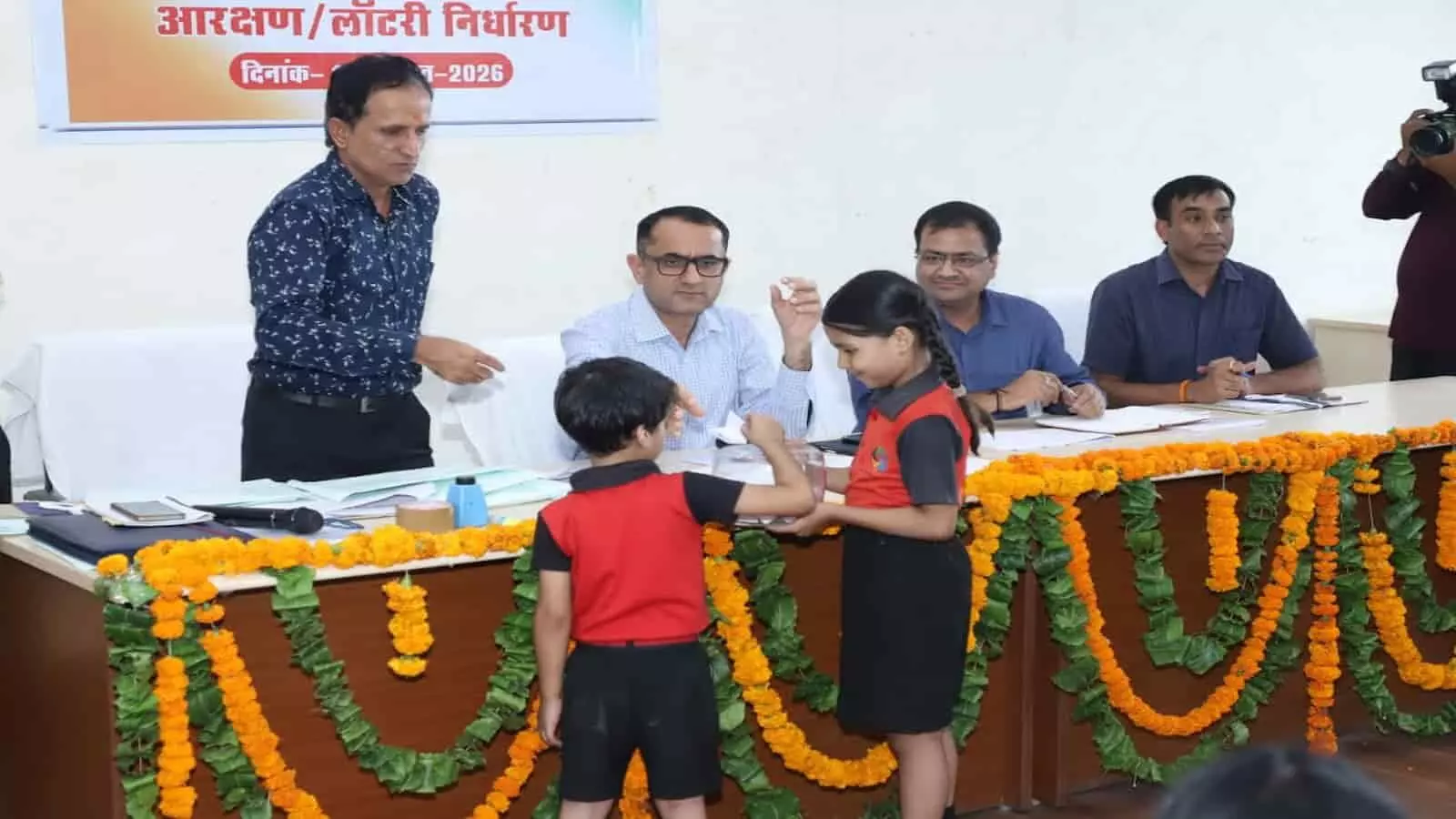 जयपुर में जिला प्रमुख पद आरक्षण लॉटरी प्रक्रिया के दौरान बच्चे पर्ची निकालते हुए अधिकारी। जयपुर में जिला प्रमुख पद आरक्षण लॉटरी प्रक्रिया के दौरान बच्चे पर्ची निकालते हुए अधिकारी।