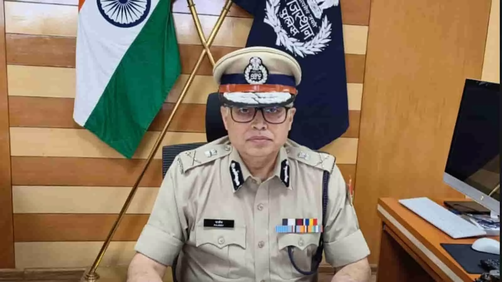 तस्वीर में पुलिस अधिकारी कार्यालय में बैठे हैं जिनके पीछे तिरंगा और पुलिस ध्वज है। तस्वीर में पुलिस अधिकारी कार्यालय में बैठे हैं जिनके पीछे तिरंगा और पुलिस ध्वज है।