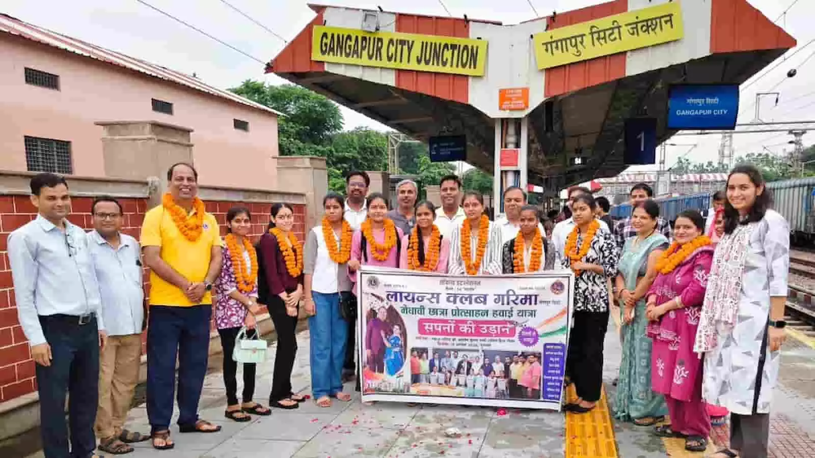 गंगापुर सिटी रेलवे स्टेशन के प्लेटफॉर्म पर बैनर के साथ खड़ी छात्राएं और लायंस क्लब के सदस्य। गंगापुर सिटी रेलवे स्टेशन के प्लेटफॉर्म पर बैनर के साथ खड़ी छात्राएं और लायंस क्लब के सदस्य।
