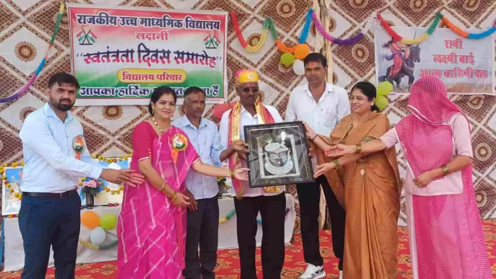 तस्वीर में नांदवेल विद्यालय के स्वतंत्रता दिवस समारोह में अतिथि एक व्यक्ति को तस्बीर और उपहार भेंट करते दिख रहे हैं। तस्वीर में नांदवेल विद्यालय के स्वतंत्रता दिवस समारोह में अतिथि एक व्यक्ति को तस्बीर और उपहार भेंट करते दिख रहे हैं।