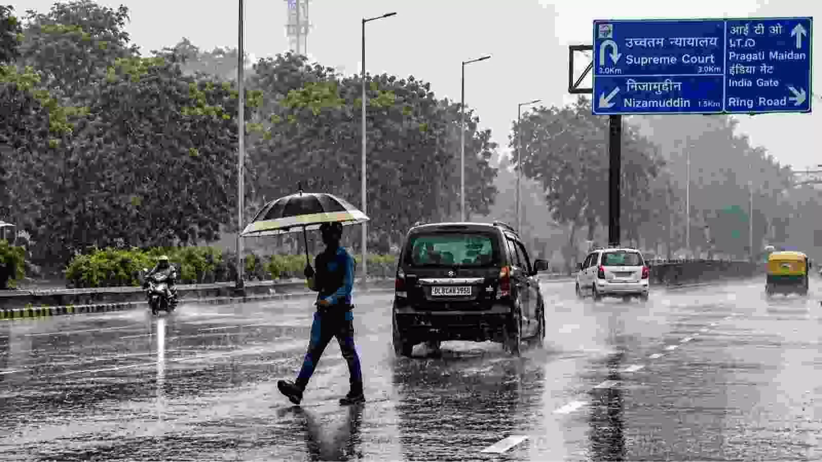 बारिश के दौरान सड़क पर छतरी लेकर चलते हुए व्यक्ति का दिल्ली में मौसम बदलाव के संदर्भ में दृश्य। बारिश के दौरान सड़क पर छतरी लेकर चलते हुए व्यक्ति का दिल्ली में मौसम बदलाव के संदर्भ में दृश्य।