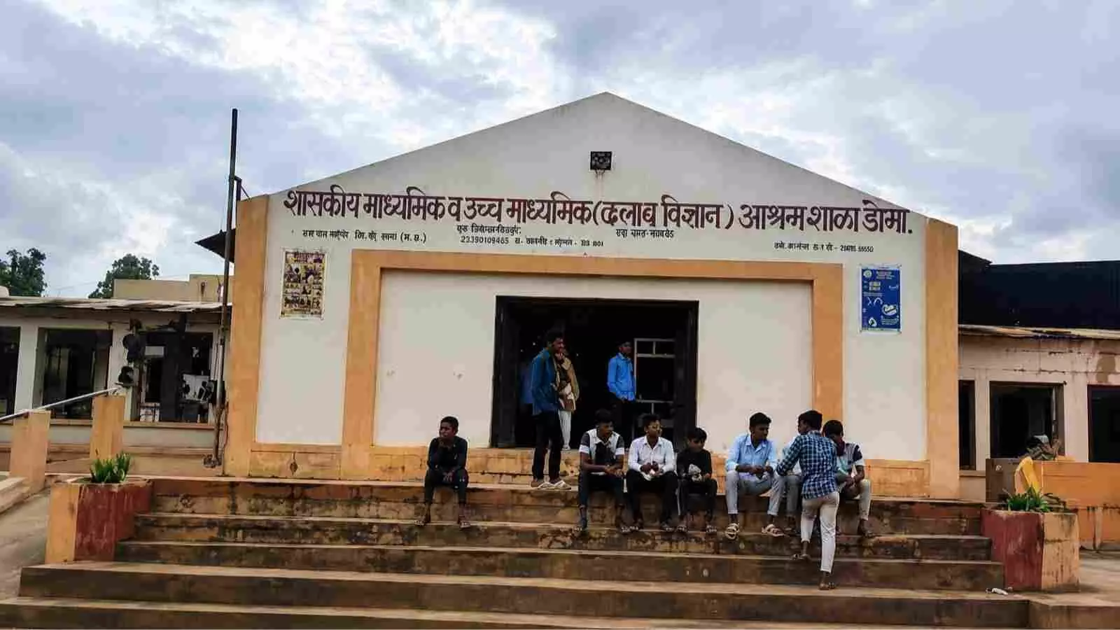 सरकारी आश्रम स्कूल की इमारत के बाहर सीढ़ियों पर बैठे छात्र| सरकारी आश्रम स्कूल की इमारत के बाहर सीढ़ियों पर बैठे छात्र|
