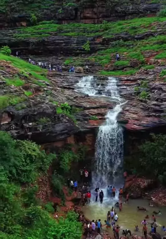 अरावली की पहाड़ियों में बहते झरने के नीचे कुंड में स्नान करते लोग और पर्यटक। अरावली की पहाड़ियों में बहते झरने के नीचे कुंड में स्नान करते लोग और पर्यटक।