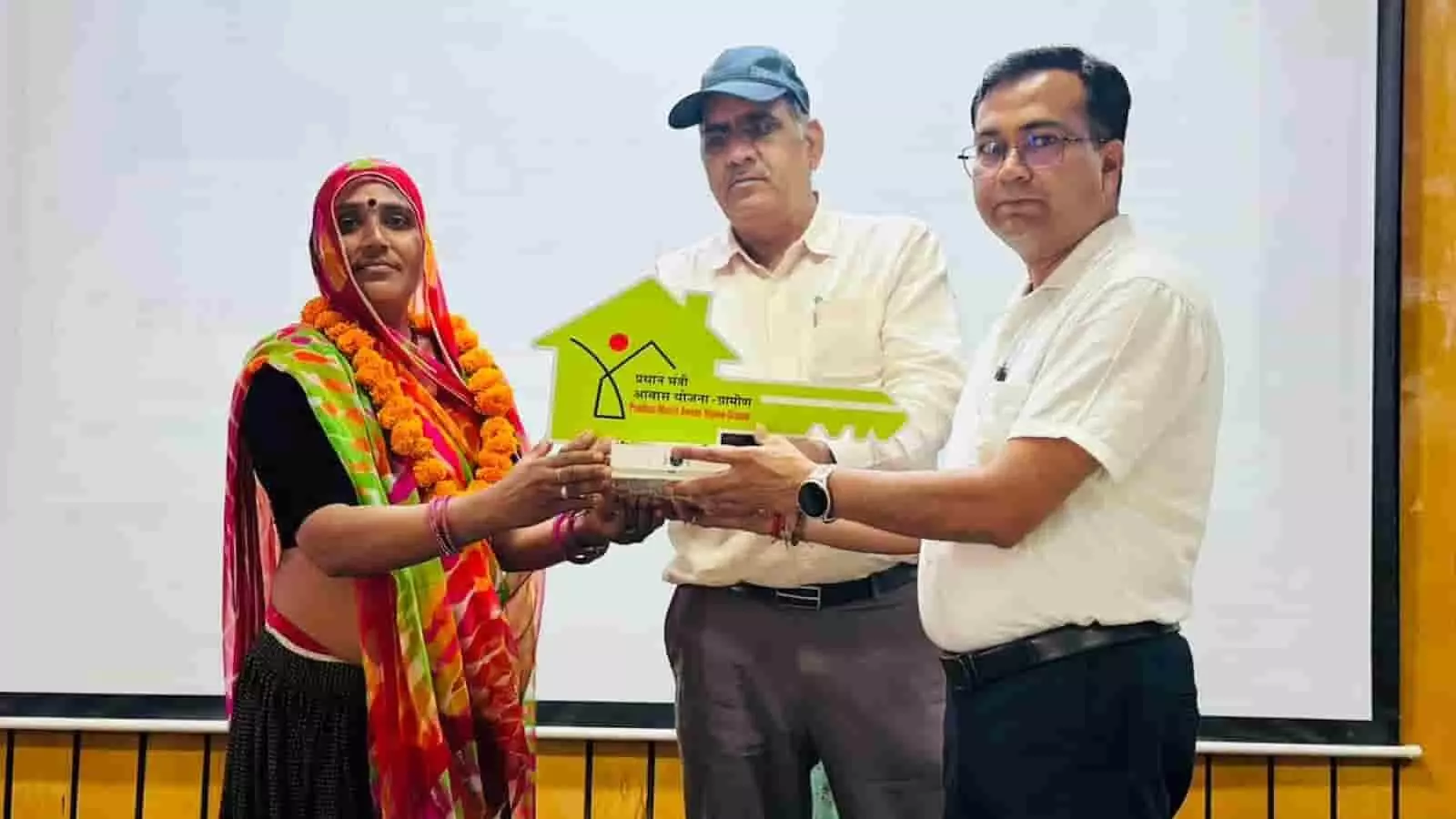 तस्वीर में महिला लाभार्थी को प्रधानमंत्री आवास योजना की प्रतीकात्मक चाबी भेंट की जा रही है। तस्वीर में महिला लाभार्थी को प्रधानमंत्री आवास योजना की प्रतीकात्मक चाबी भेंट की जा रही है।