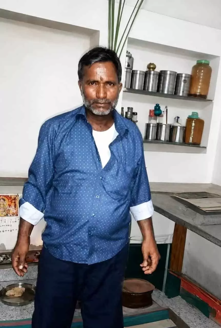 नीली शर्ट पहने किसान कल्याण नाथ घर के अंदर खड़े दिखाई दे रहे हैं। नीली शर्ट पहने किसान कल्याण नाथ घर के अंदर खड़े दिखाई दे रहे हैं।
