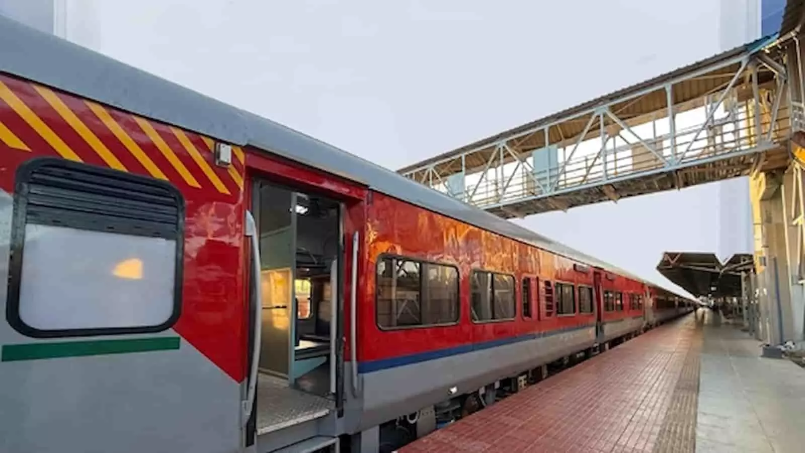 रेलवे स्टेशन पर प्लेटफॉर्म पर खड़ी लाल और स्लेयी रंग की एक्सप्रेस ट्रेन दिखाई दे रही है। रेलवे स्टेशन पर प्लेटफॉर्म पर खड़ी लाल और स्लेयी रंग की एक्सप्रेस ट्रेन दिखाई दे रही है।