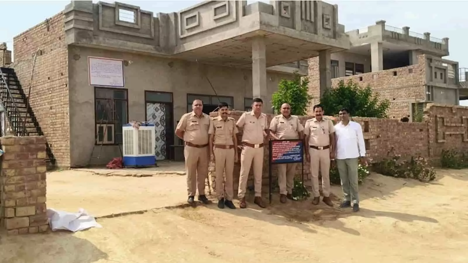 तस्वीर में पुलिस अधिकारी और एक व्यक्ति निर्माणाधीन इमारत के सामने खड़े हैं। तस्वीर में पुलिस अधिकारी और एक व्यक्ति निर्माणाधीन इमारत के सामने खड़े हैं।