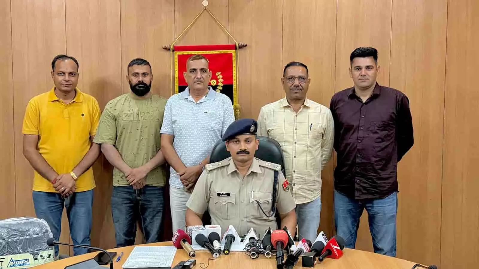 तस्वीर में मेज के आगे बैठे पुलिस अधिकारी और पीछे खड़े पुलिसकर्मी नजर आ रहे हैं। तस्वीर में मेज के आगे बैठे पुलिस अधिकारी और पीछे खड़े पुलिसकर्मी नजर आ रहे हैं।