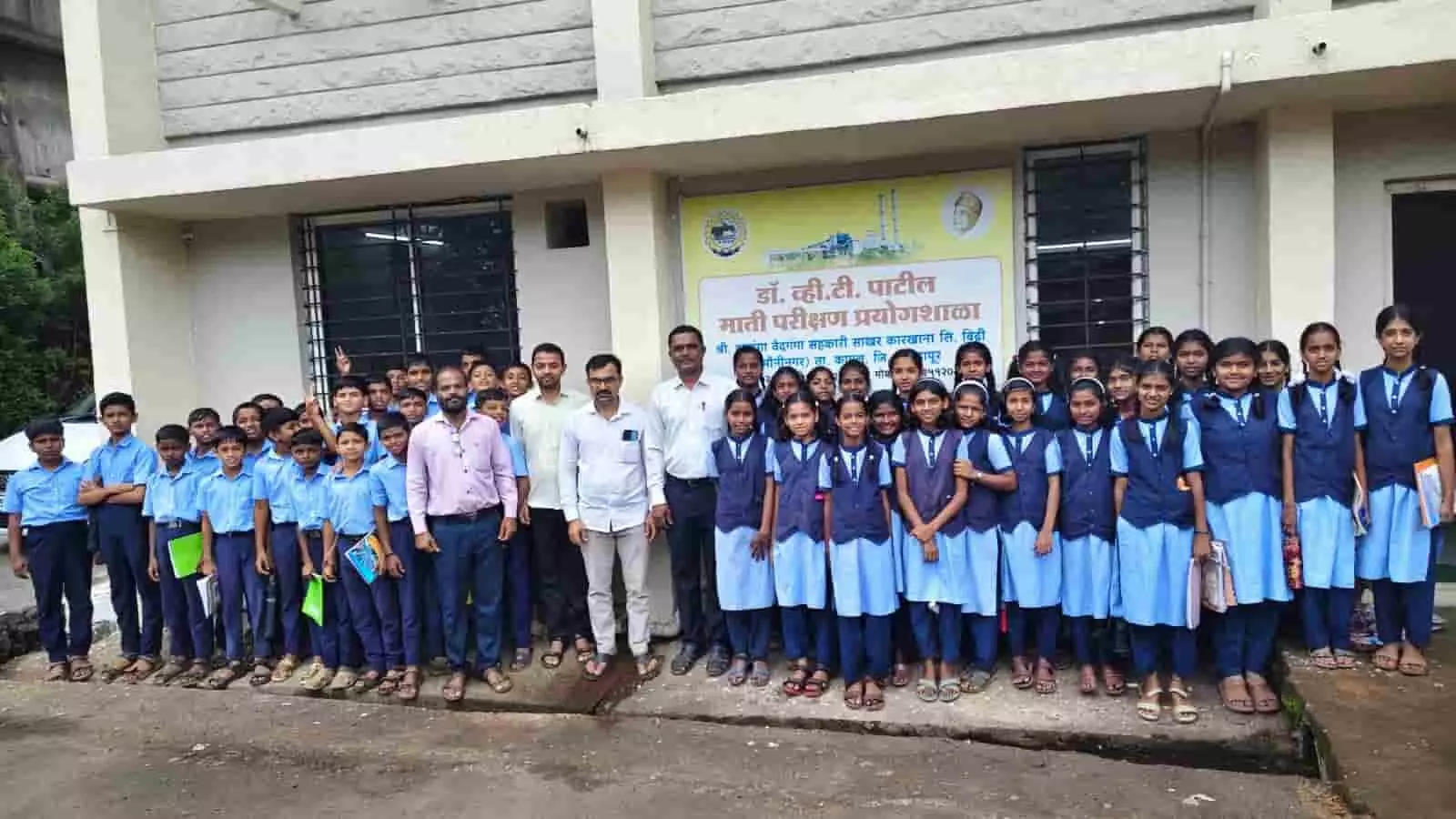 तस्वीर में नीले और सफेद गणवेश में छात्र और शिक्षक माती परीक्षण प्रयोगशाळेच्या फलकासमोर उभे दिखाई दे रहे हैं। तस्वीर में नीले और सफेद गणवेश में छात्र और शिक्षक माती परीक्षण प्रयोगशाळेच्या फलकासमोर उभे दिखाई दे रहे हैं।