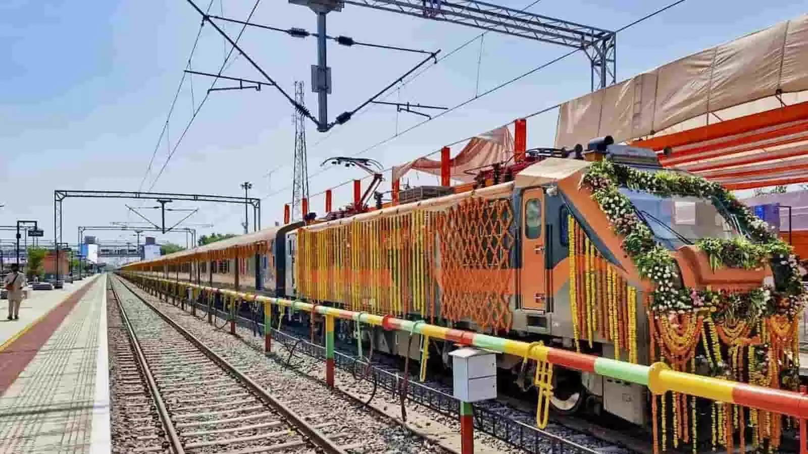 तस्वीर में फूलों से सजी अमृत भारत एक्सप्रेस ट्रेन रेलवे स्टेशन पर ट्रैक पर खड़ी है। तस्वीर में फूलों से सजी अमृत भारत एक्सप्रेस ट्रेन रेलवे स्टेशन पर ट्रैक पर खड़ी है।