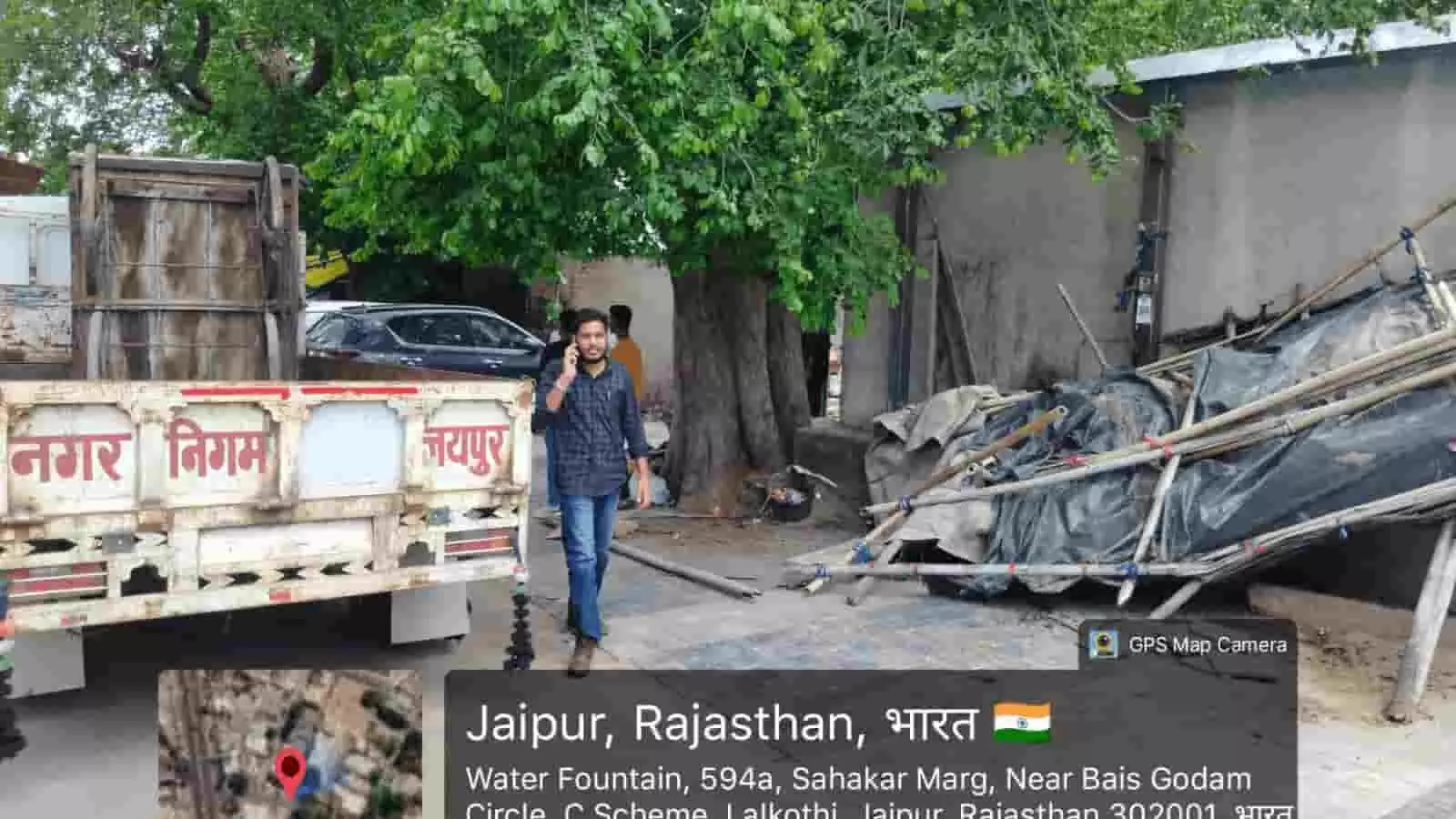 नगर निगम के वाहन और सामान के पास सड़क पर खड़े व्यक्ति की तस्वीर। नगर निगम के वाहन और सामान के पास सड़क पर खड़े व्यक्ति की तस्वीर।