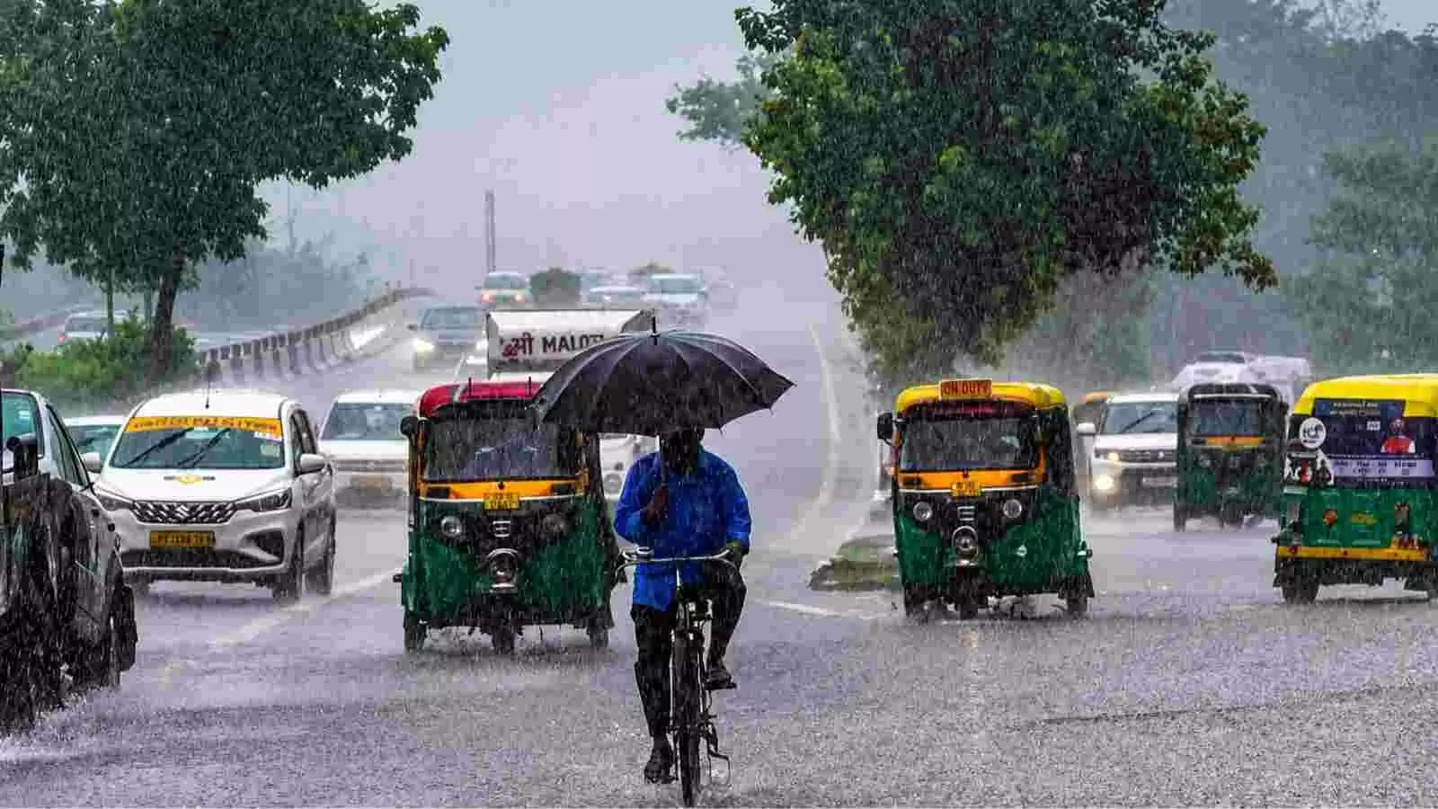 बारिश के दौरान दिल्ली की सड़क पर साइकिल चलाते हुए व्यक्ति और वाहन नजर आ रहे हैं| बारिश के दौरान दिल्ली की सड़क पर साइकिल चलाते हुए व्यक्ति और वाहन नजर आ रहे हैं|