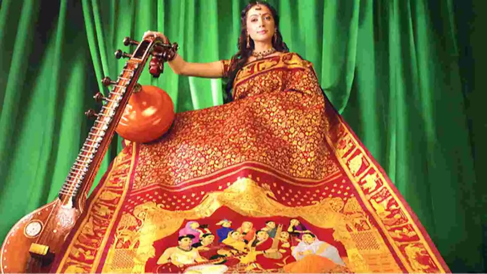 पारंपरिक वेशभूषा में सजी महिला राजा रवि वर्मा की पेंटिंग्स और कीमती रत्नों से जड़ी विवाह पट्टू साड़ी प्रदर्शित कर रही है। पारंपरिक वेशभूषा में सजी महिला राजा रवि वर्मा की पेंटिंग्स और कीमती रत्नों से जड़ी विवाह पट्टू साड़ी प्रदर्शित कर रही है।