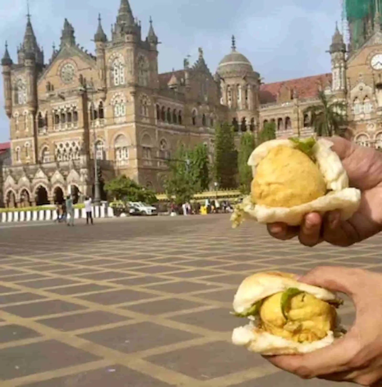 छत्रपति शिवाजी महाराज टर्मिनस के सामने हाथ में वड़ा पाव पकड़े हुए व्यक्ति की तस्वीर। छत्रपति शिवाजी महाराज टर्मिनस के सामने हाथ में वड़ा पाव पकड़े हुए व्यक्ति की तस्वीर।